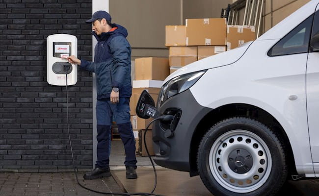 Chauffeur bij elektrische paal met bedrijfsauto