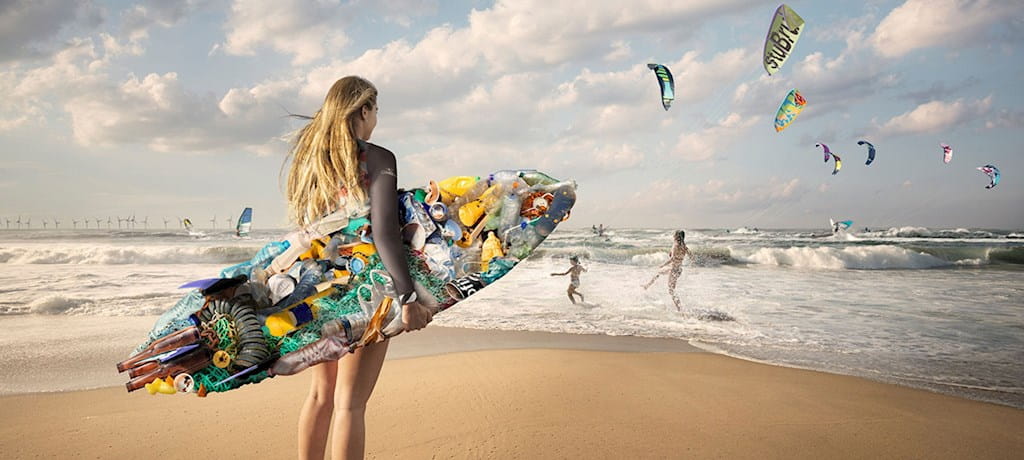 Een surfster staat op het strand met een surfplank gemaakt van afval