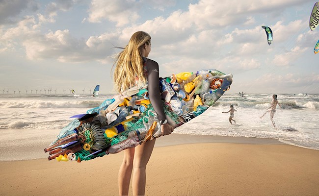 Een surfster staat op het strand met een surfplank gemaakt van afval