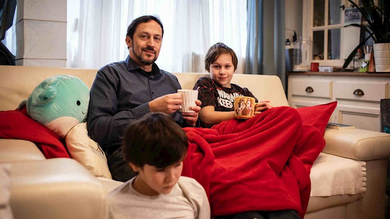 David sur le canapé avec ses deux fils et une couverture chaude