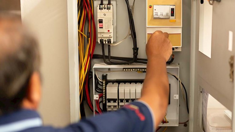 Een electricien aan het werk in een meterkast