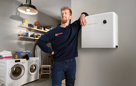 Een Eneco technieker leunt op een slimme thuisbatterij